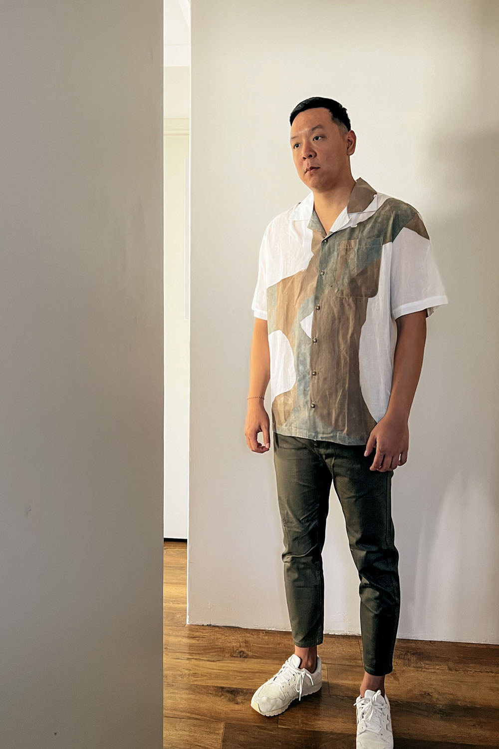 A handpainted batik cotton shirt in beige, brown, and white colors, worn by a male model