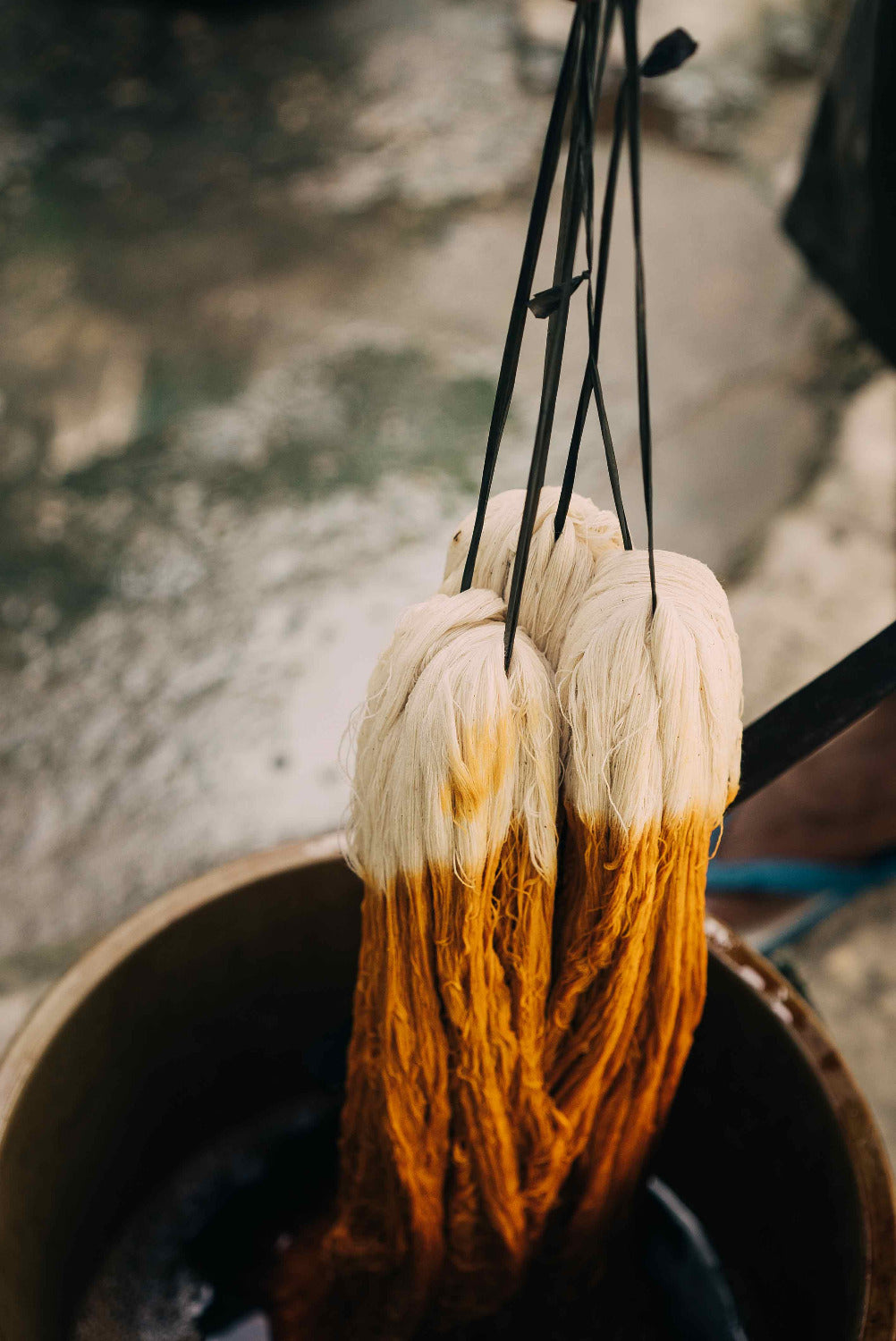 Cotton yarn being immersed in a plant-based dye bath during the natural dyeing process in Indonesia