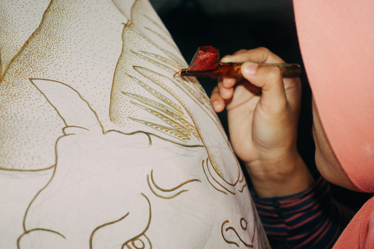 Artisan hand painting organic cotton fabric using batik wax-resist technique.