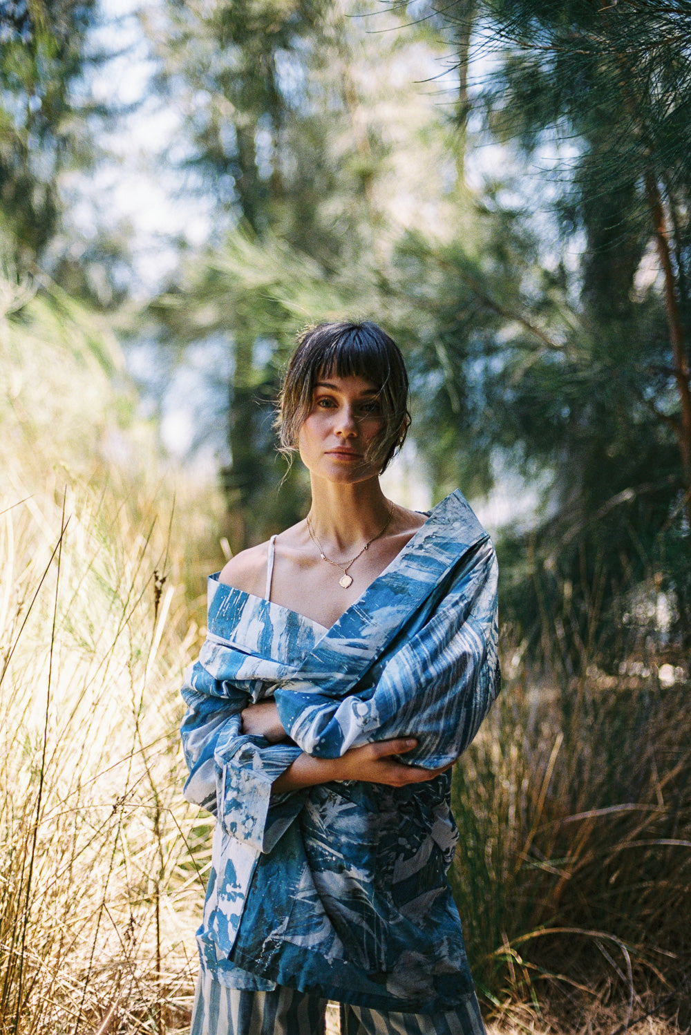 Woman in a blue patterned dress standing in a forest