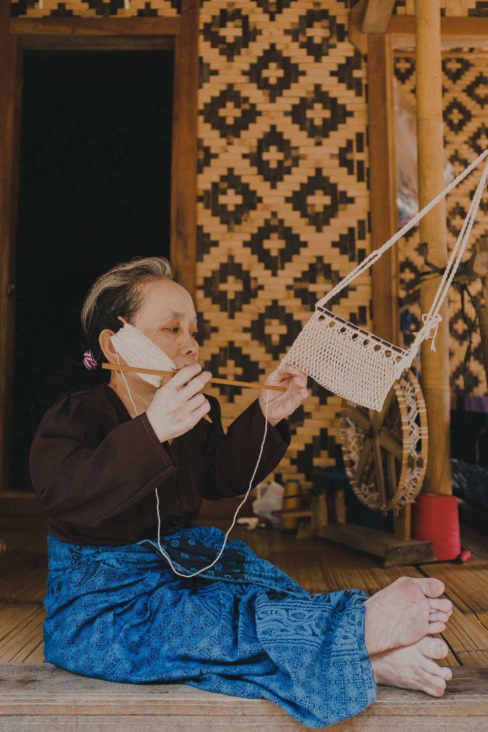 Kanekes artisan traditionally weaving fabric by hand inside a woven bamboo home