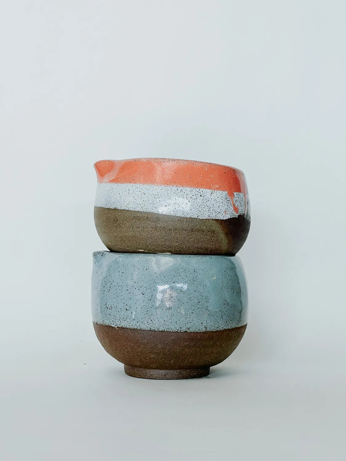Two ceramic cups stacked on a light gray background