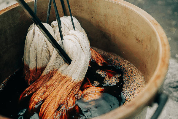 Hand-spun yarn being naturally dyed using plant-based pigments, showing the slow traditional textile process behind RŪPAHAUS garments.