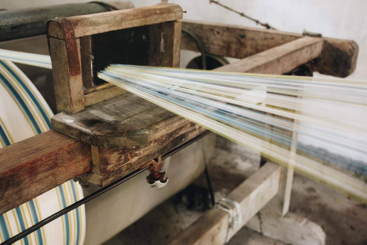 Warp threads moving through a traditional loom, showing how artisan collaboration and regional knowledge are woven into each textile used by RŪPAHAUS.