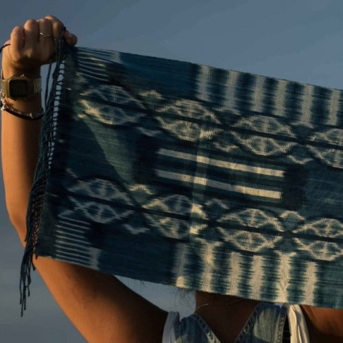 A person holding a handwoven Sumbanese indigo ikat scarf from behind - handwoven ikat, East Sumba