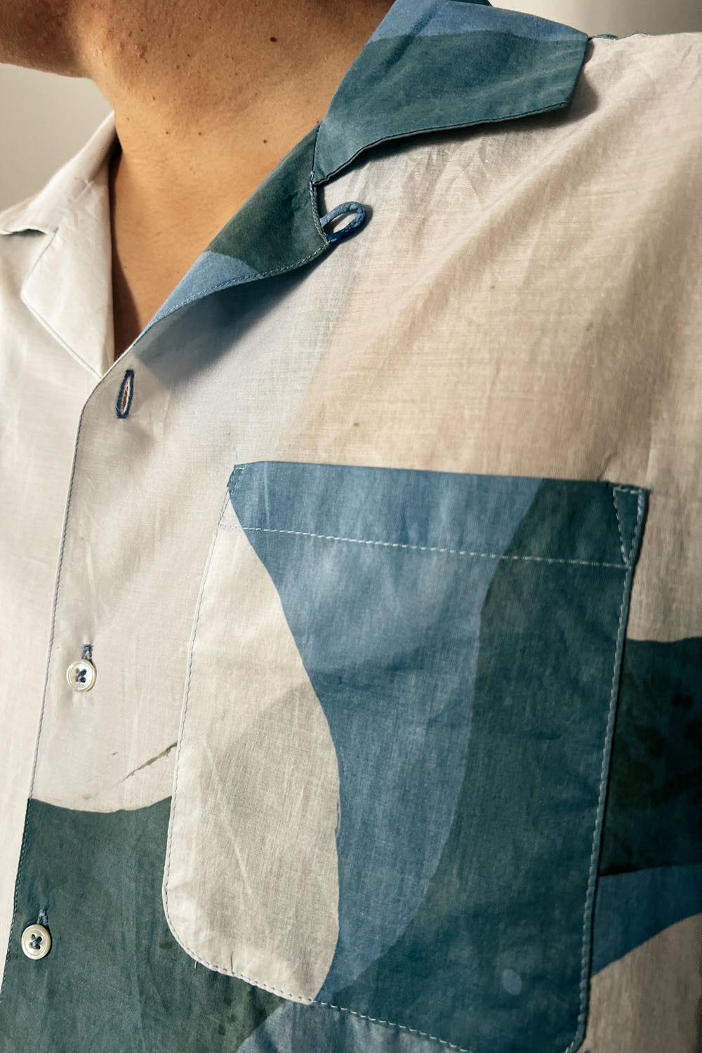 Handpainted Batik Camp Shirt in blue, green and natural hues with relaxed collar and short sleeves, worn by a male model
