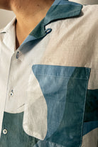 Handpainted Batik Camp Shirt in blue, green and natural hues with relaxed collar and short sleeves, worn by a male model