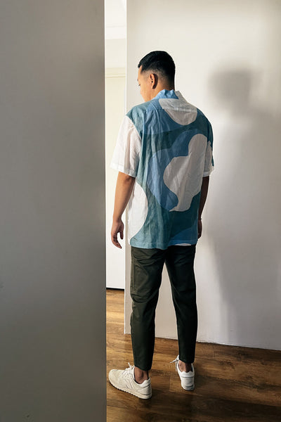 Handpainted Batik Camp Shirt in blue, green and natural hues with relaxed collar and short sleeves, worn by a male model
