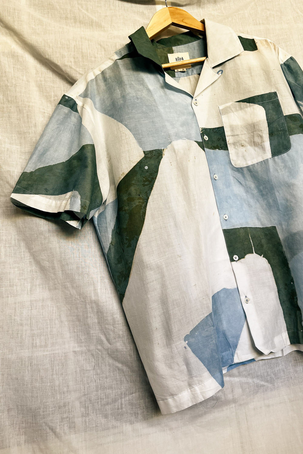 Handpainted Batik Camp Shirt in blue, green and natural hues with relaxed collar and short sleeves, worn by a male model