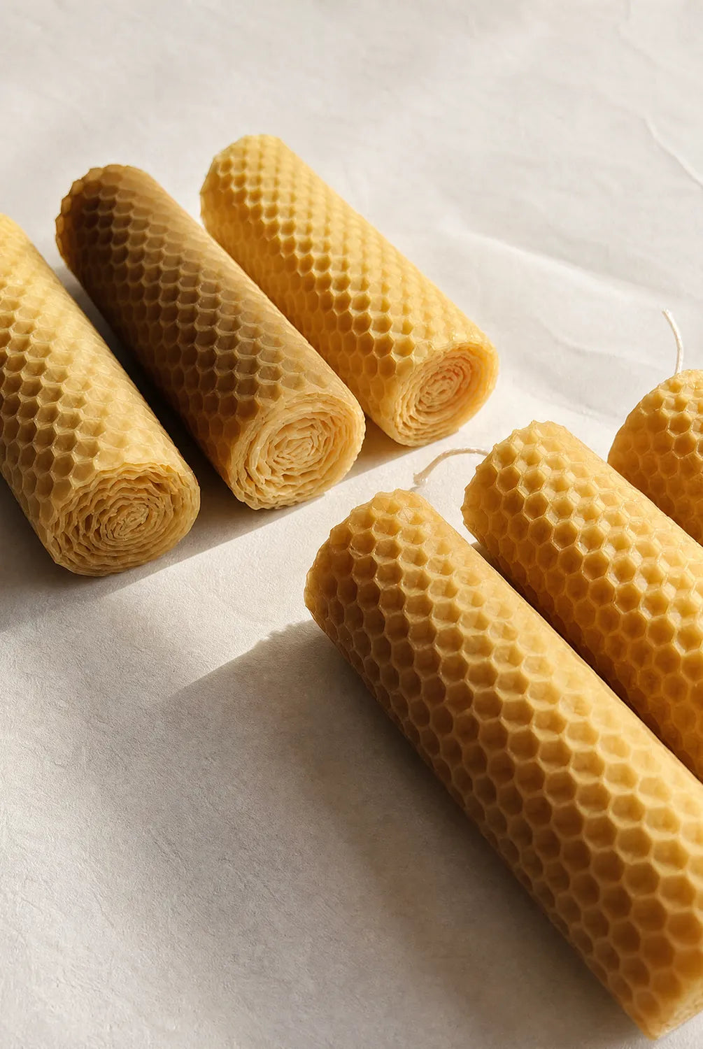 Rolls of natural beeswax candles on a light background