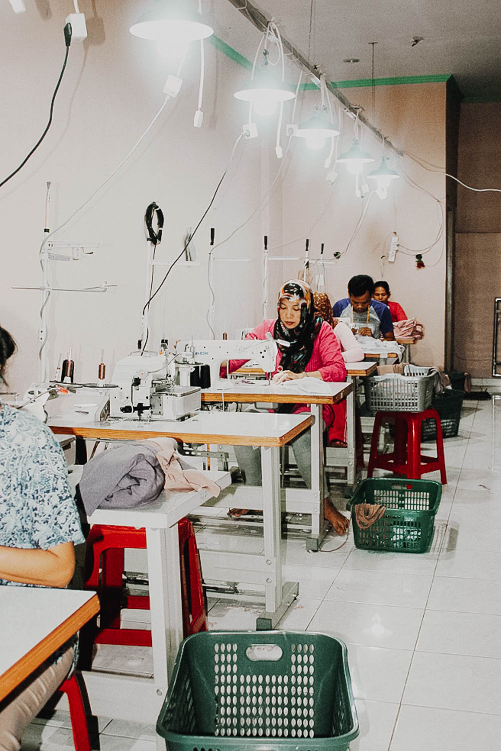Garment makers working side by side in a small-batch production workshop in Indonesia, sewing clothing with care and precision.