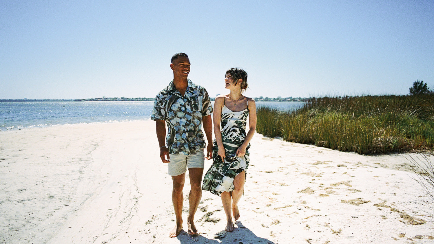 Man and woman wearing RŪPAHAUS handcrafted Indonesian clothing walking on a beach