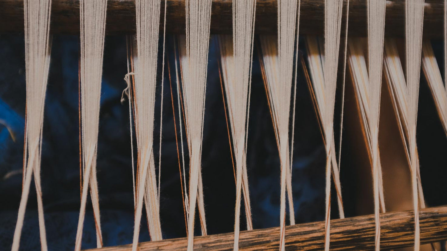 Artisan working at a handloom, weaving natural cotton threads using traditional textile methods in Indonesia.