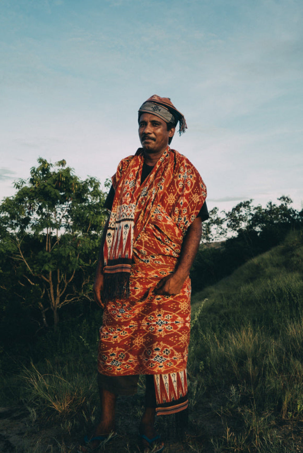 IkataArtisan wearing a handwoven patterned textile, photographed outdoors in a rural setting