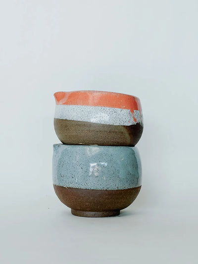 Two ceramic cups stacked on a light gray background