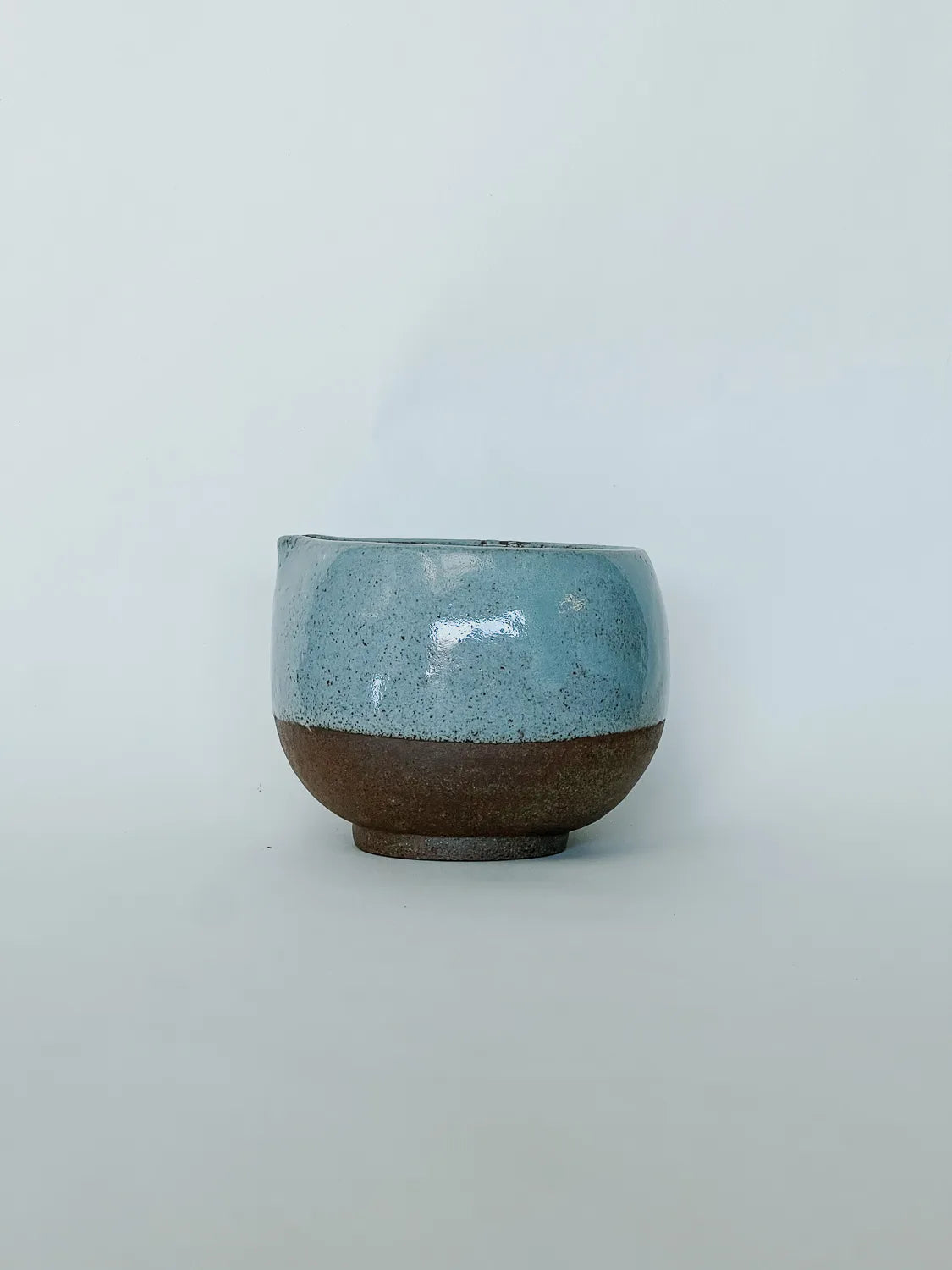 Ceramic cup with blue top and brown bottom on a light gray background