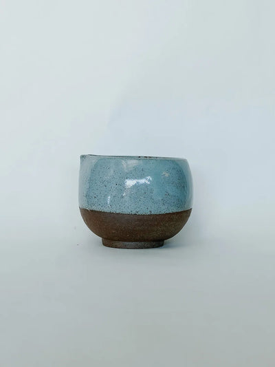 Ceramic cup with blue top and brown bottom on a light gray background