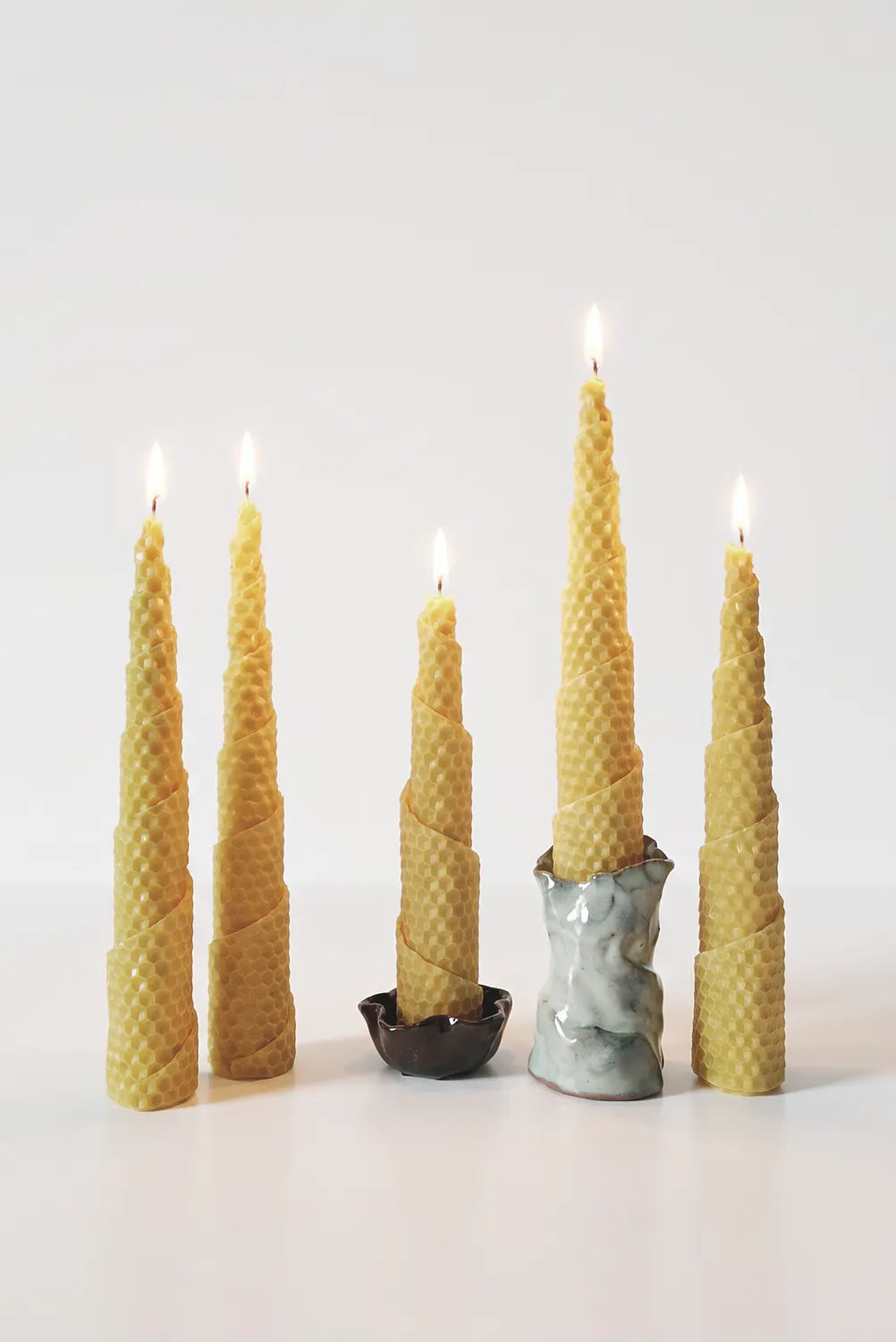 Set of five tall, pine-shaped beeswax candles with textured surfaces on a white background. Hand-rolled beeswax candles made in Perth, Western Australia — natural with subtle honey scent, sustainable and eco-friendly home décor.