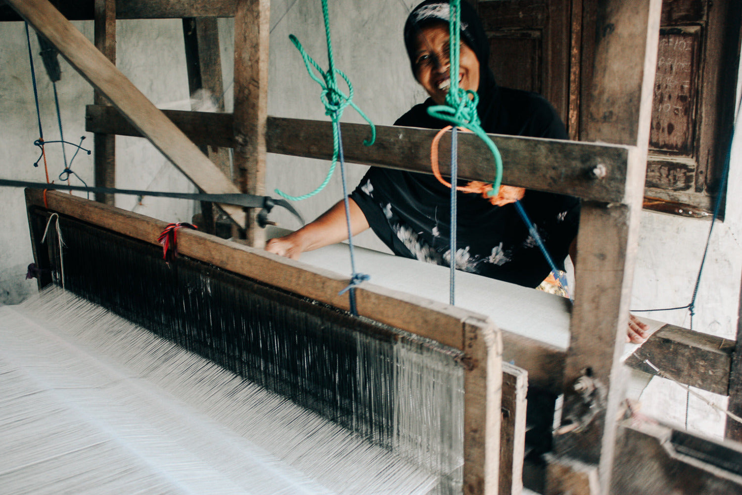 An artisan working on woven textiles in a small workshop, illustrating how seasonless clothing supports long-term partnerships, small-batch production, and reduced inventory waste.