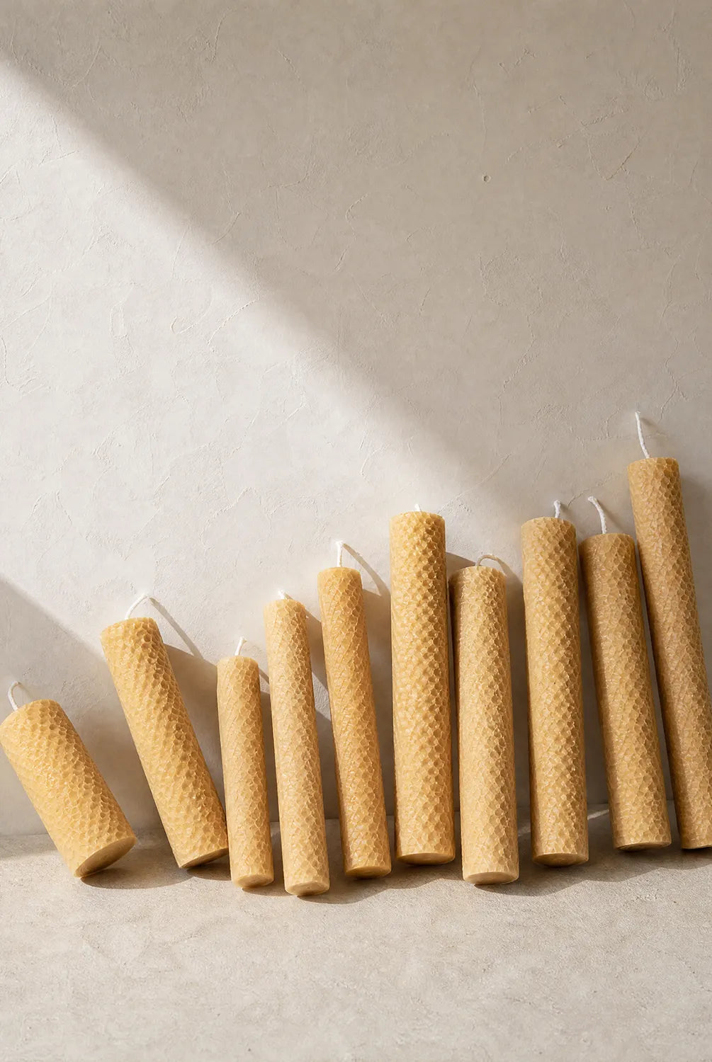 Row of natural beeswax candles on a light background, Hand-rolled beeswax candles with subtle honey scent, sustainable and eco-friendly home décor, made in Perth, Western Australia.