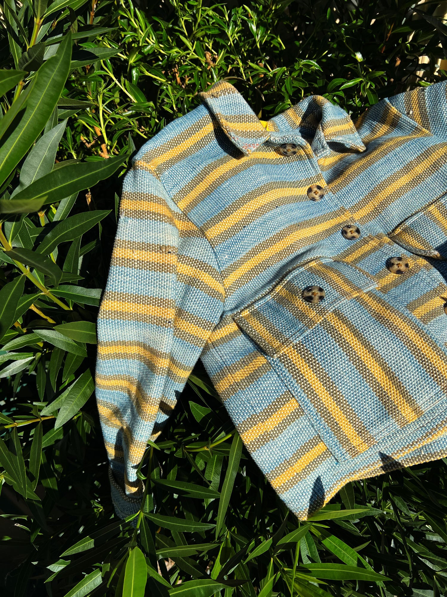 Handwoven striped jacket made from natural fibres, photographed outdoors to represent seasonless clothing designed for long-term wear.