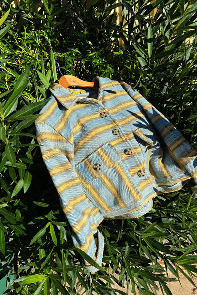 Handwoven striped jacket made from natural fibres, photographed outdoors to represent seasonless clothing designed for long-term wear.