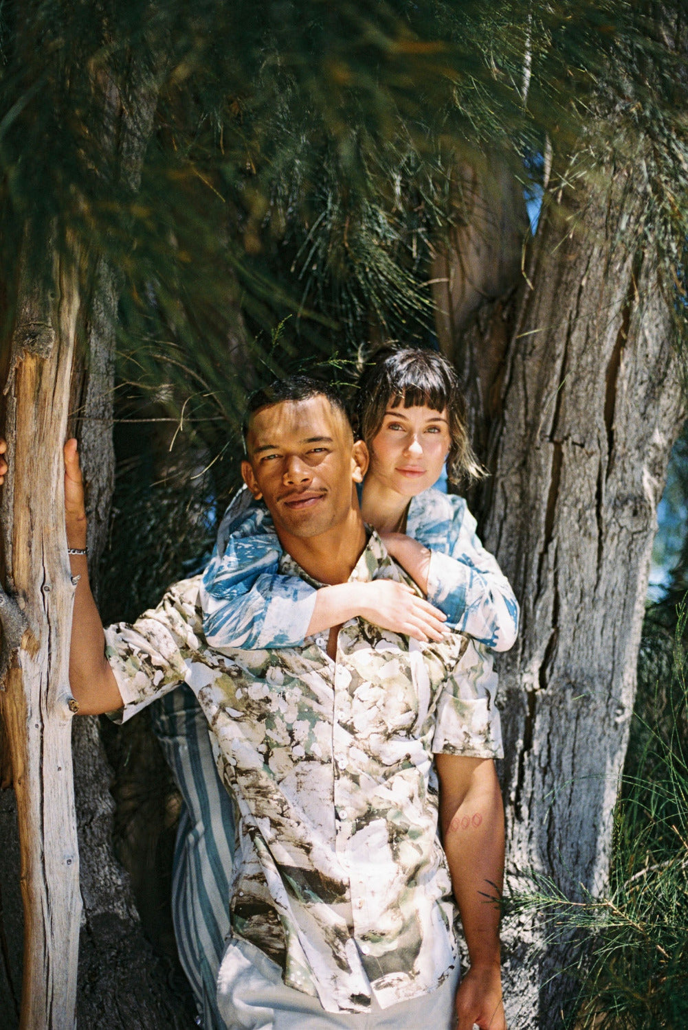 A man and a woman wearing lightweight natural-fibre clothing outdoors, showing seasonless garments designed for everyday movement, layering, and long-term wear.