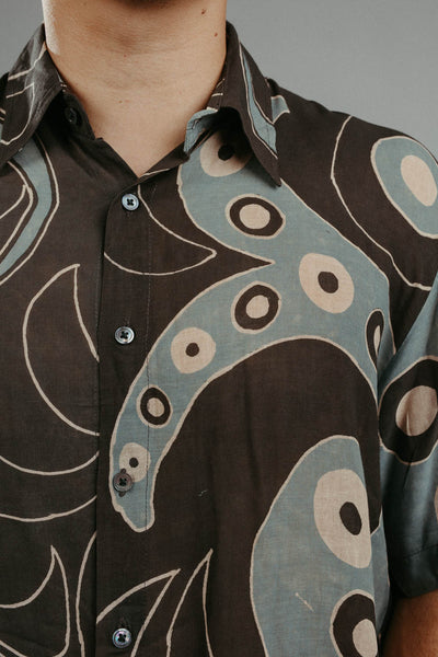 detail shot of a brown handpainted batik shirt with a geometric pattern featuring circles and lines.