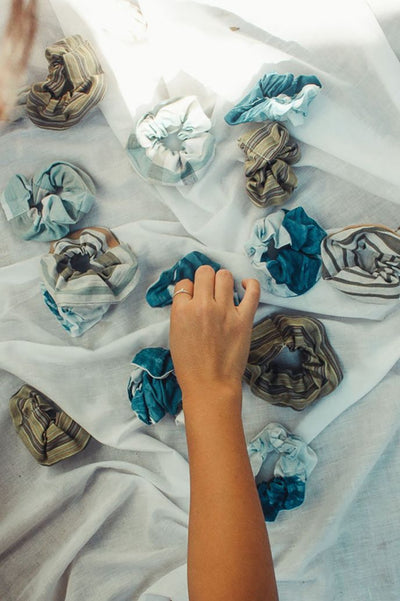 Hand arranging handmade RŪPAHAUS scrunchies as a RE:RUPA upcycled program, crafted from organic cotton offcuts, dyed using natural plant-based colours.